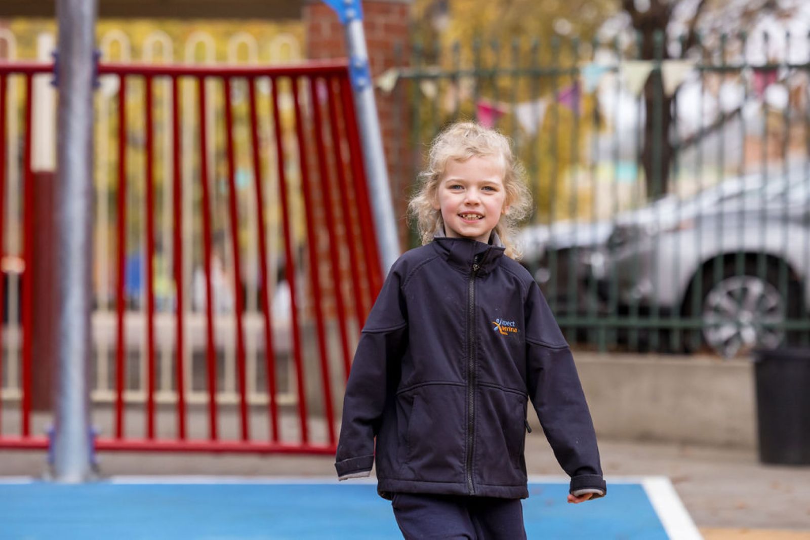 Young student smiling while walking across playground
