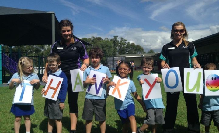 Students and staff holding out a poster that says 'thankyou' at Aspect Hunter School